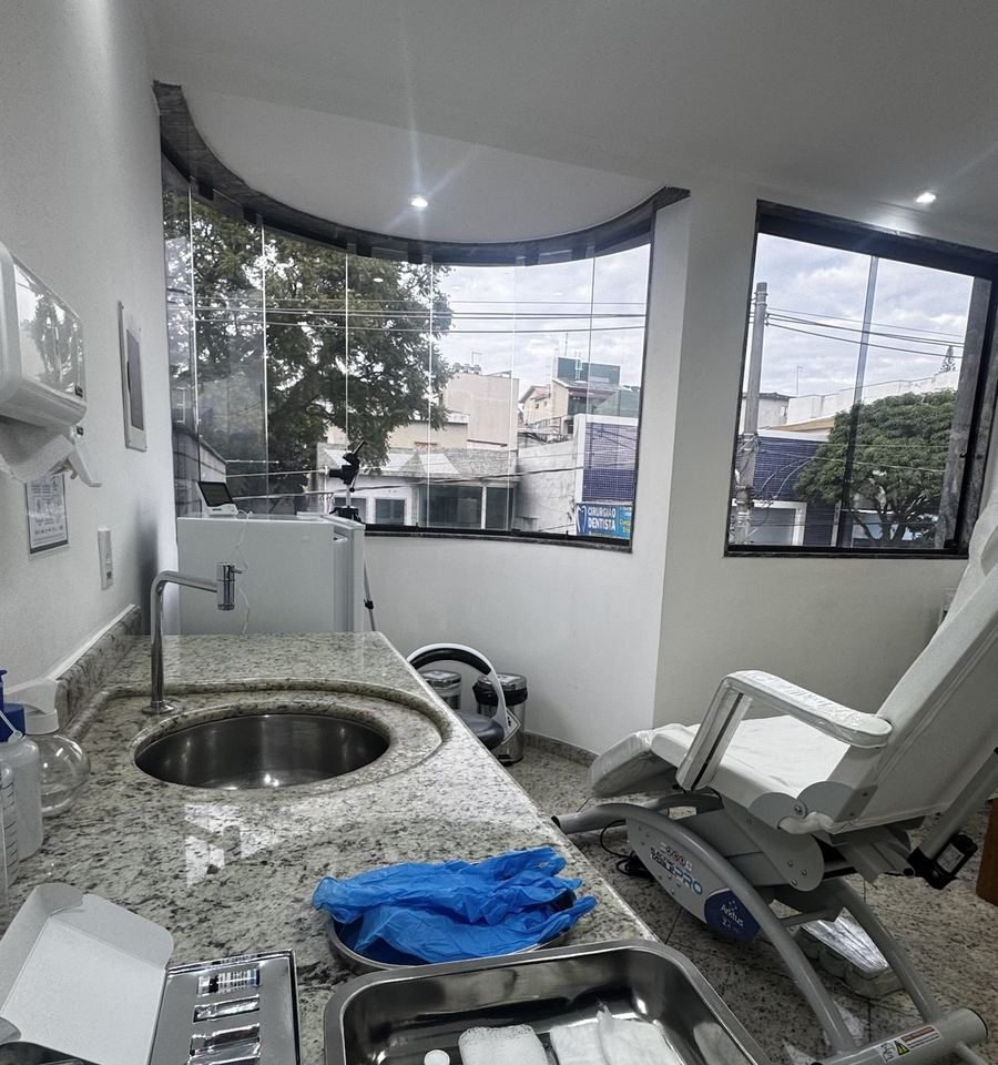 Sala de procedimentos com poltrona, bancada e janelas amplas